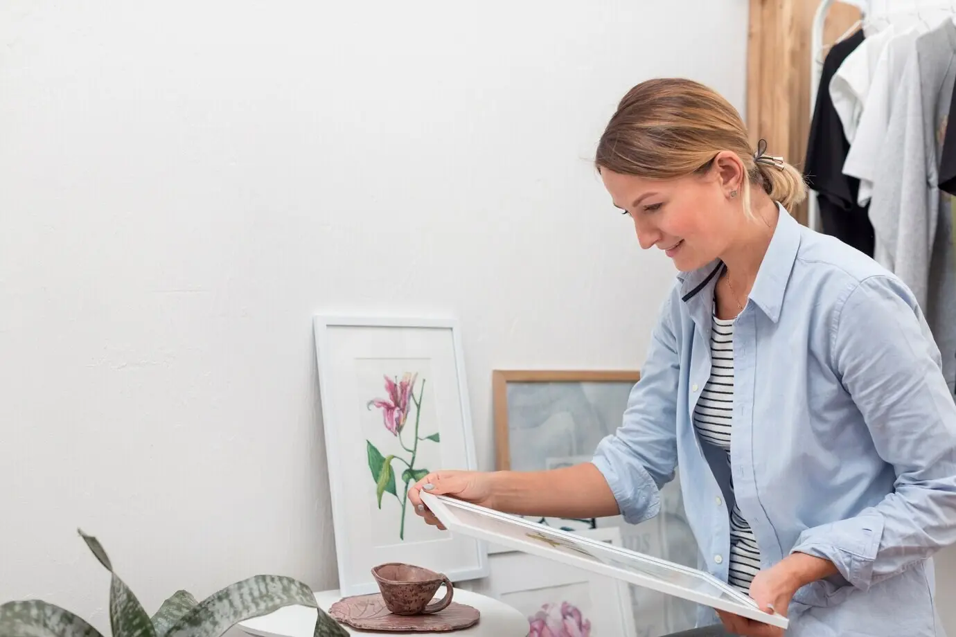 Seitenansicht einer Frau, die ein Blumengemälde hält.